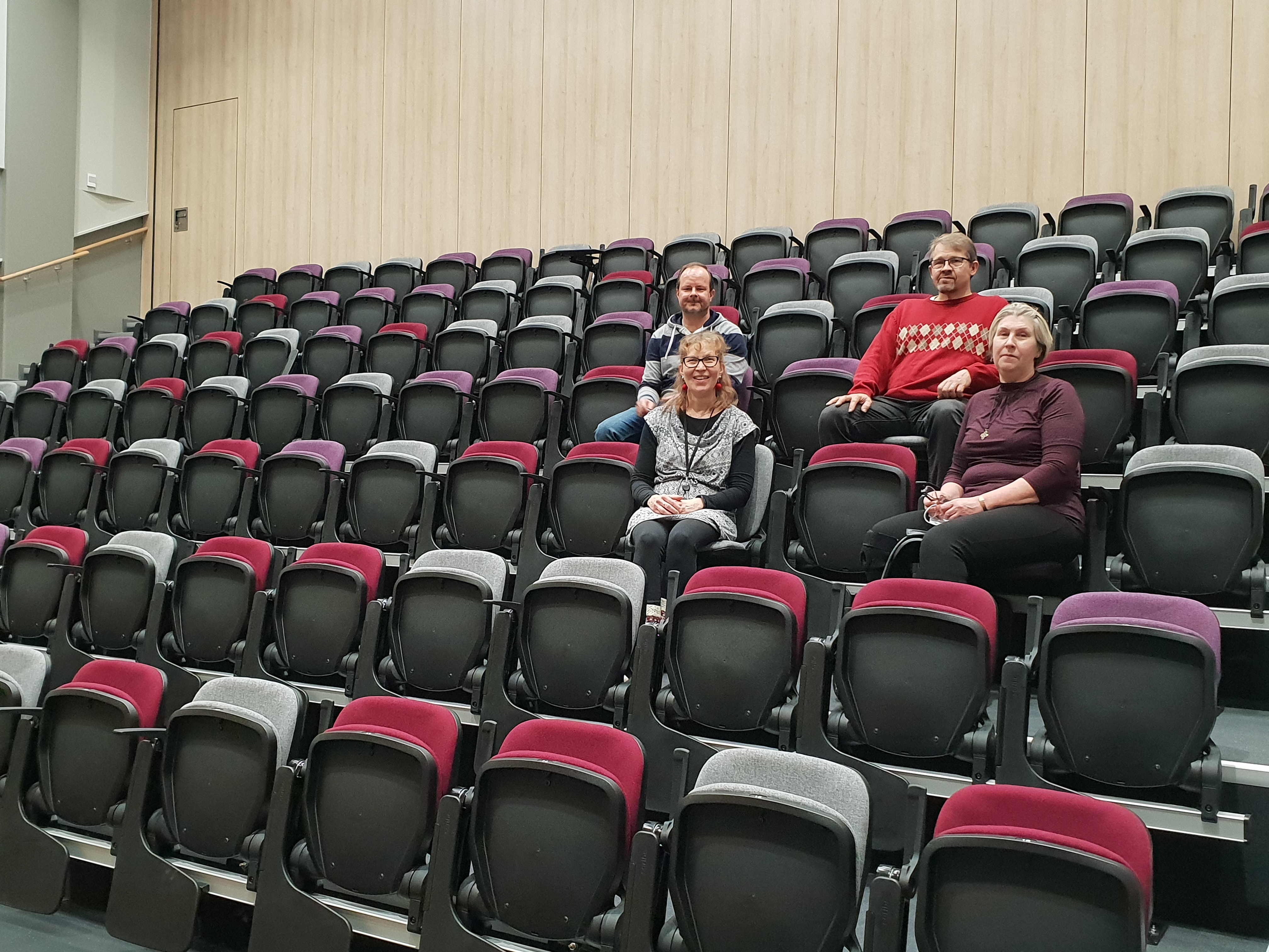 Kampuksen vastavalmistuneessa auditoriossa istuu neljä ihmistä.